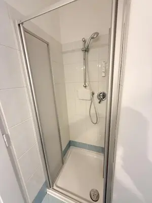 a shower with a glass door in a bathroom at Cozy city center apartment in Bolzano