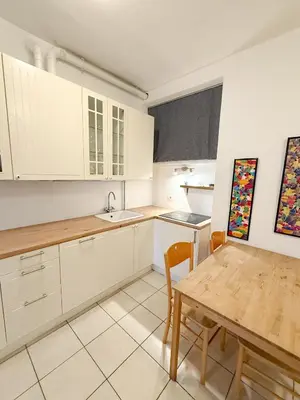 a kitchen with white cabinets and a wooden table at Cozy city center apartment in Bolzano