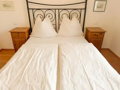 a white bed with white sheets and pillows at Cozy city center apartment in Bolzano