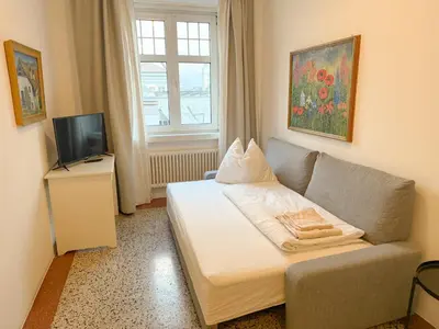a room with a bed and a couch and a television at Cozy city center apartment in Bolzano