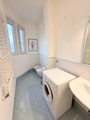 a white bathroom with a washing machine and a toilet at Cozy city center apartment in Bolzano