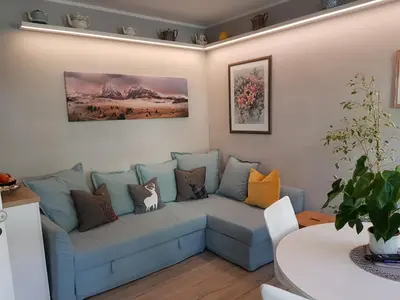 a living room with a blue couch with pillows at Downtown Hideout Bressanone Pedestrian Zone Private Garden, Parking Brixen Card in Bressanone