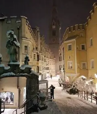 a city street at night with a clock tower at Downtown Hideout Bressanone Pedestrian Zone Private Garden, Parking Brixen Card in Bressanone