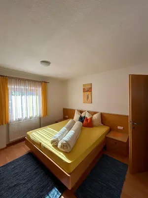 a bedroom with a yellow bed with pillows on it at Appartements Schatzer in Valdaora