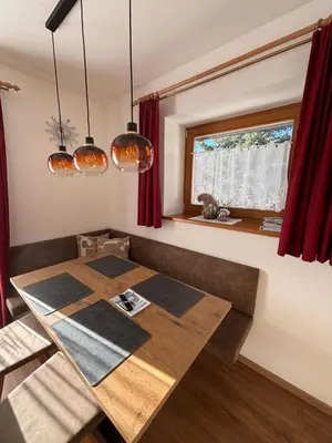 a dining room with a wooden table and red curtains at Appartements Schatzer in Valdaora