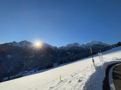 a snow covered mountain with the sun in the sky at Appartements Schatzer in Valdaora