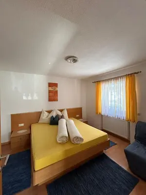 a bedroom with a yellow bed and a blue rug at Appartements Schatzer in Valdaora