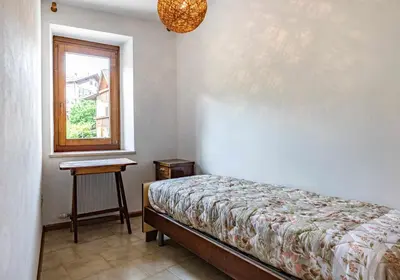 a bedroom with a bed and a window and a table at Dimora Franch Cloz Ospitar in Cloz