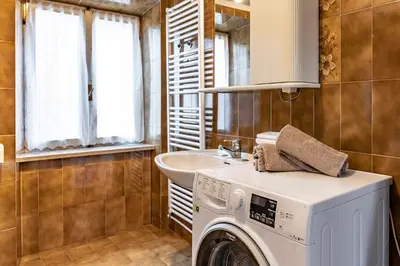 a bathroom with a washing machine and a sink at Dimora Franch Cloz Ospitar in Cloz