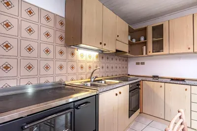 a kitchen with wooden cabinets and a sink at Dimora Franch Cloz Ospitar in Cloz