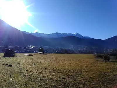 a field with the sun shining on a mountain at Casa Rosetta nel cuore delle Dolomiti in Tonadico