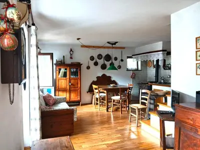 a kitchen and living room with a table and chairs at Casa Rosetta nel cuore delle Dolomiti in Tonadico