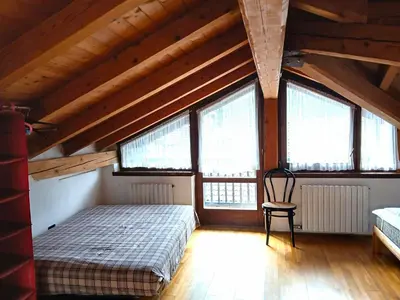 a bedroom with a bed and a chair in a attic at Casa Rosetta nel cuore delle Dolomiti in Tonadico