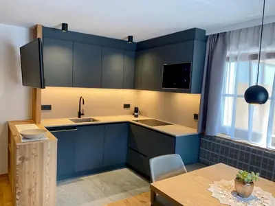 a kitchen with blue cabinets and a table and a window at Ciasa La Rösa in Badia