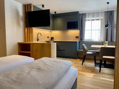 a hotel room with a kitchen and a dining room at Ciasa La Rösa in Badia