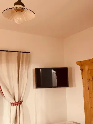 a flat screen tv on a wall with a curtain at Braunegg 1 in Brunico