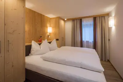 a bedroom with a large white bed with a window at Ciasa Col Cuch in La Villa