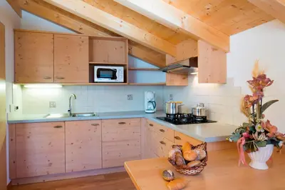 a kitchen with wooden cabinets and a wooden table at Ciasa Col Cuch in La Villa