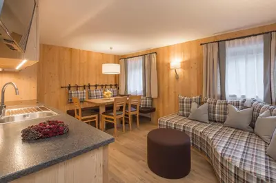 a kitchen and living room with a couch and a table at Ciasa Col Cuch in La Villa