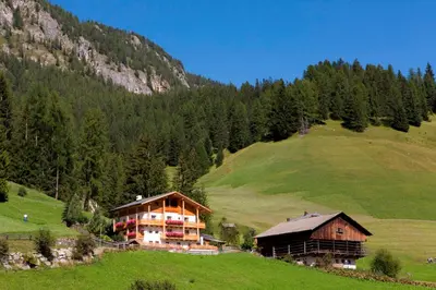 a large building on a hill in a field at Ciasa Col Cuch in La Villa