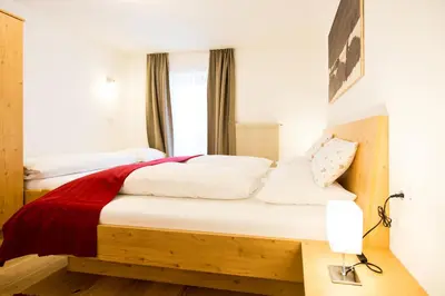 a bedroom with two beds with white sheets and a red blanket at Reden Hof in Selva dei Molini