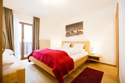 a bedroom with a large bed with a red blanket at Reden Hof in Selva dei Molini