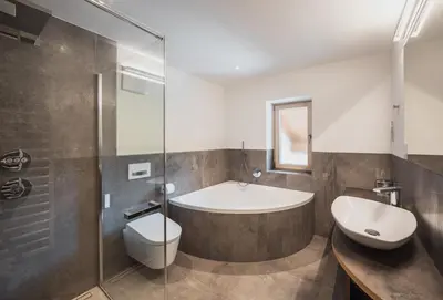 a bathroom with a tub and a toilet and a sink at Hotel Bischofhof in Chiusa