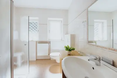 a bathroom with a sink and a toilet and a mirror at Hotel Bischofhof in Chiusa