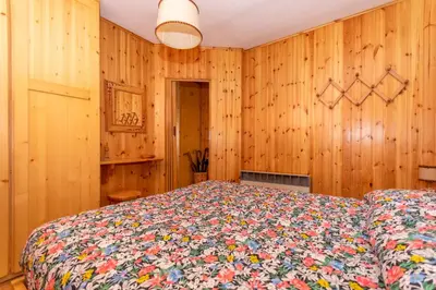 a bedroom with wooden walls and a bed with a colorful bedspread at Casa Coli in Mazzin