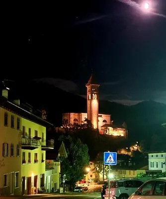 a building with a clock tower on a hill at night at TERRAZZA SULLE DOLOMITI in Castello di Fiemme