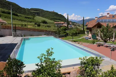 a large blue swimming pool in a yard with a house at Huebenburg in Appiano sulla Strada del Vino