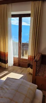 a bedroom with a bed and a sliding glass door at Waldhof in Meltina