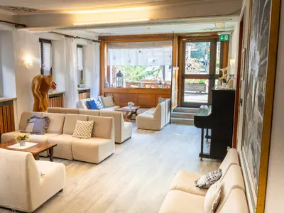 a living room with couches and a piano at Hotel Alle Alpi in Alleghe