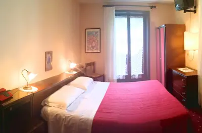 a bedroom with a large bed with a red blanket at Hotel Alle Alpi in Alleghe