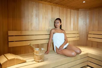 a woman is sitting in a sauna at Wellness e Resort Stella Delle Alpi in Ronzone