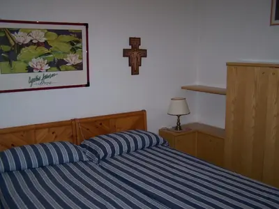 a bedroom with a bed with a cross on the wall at Appartamenti Katinanna in Alleghe