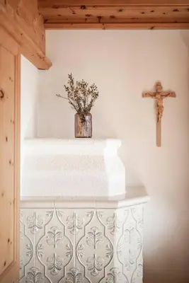 a church altar with a cross and a vase of flowers at Radhof in Villandro