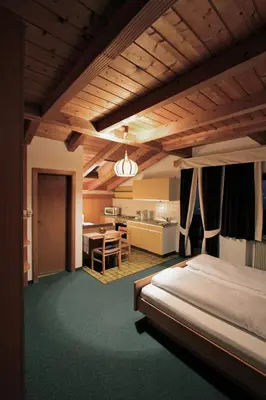 a bedroom with a bed and a table and a kitchen at Residence Baumgartner in Fiè