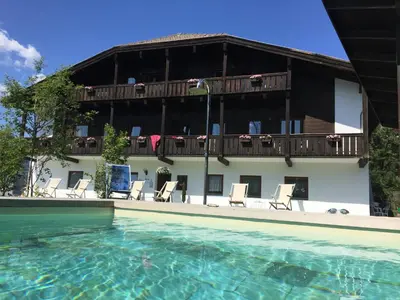 a hotel with a swimming pool with chairs and a building at Residence Baumgartner in Fiè