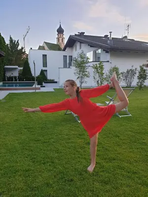 a girl in a red dress dancing in the grass at Residence Baumgartner in Fiè