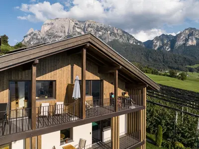 a house with a balcony and mountains in the background at Appartements Panorama in Fiè