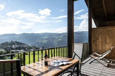 a table with a bottle of wine on a balcony at Appartements Panorama in Fiè