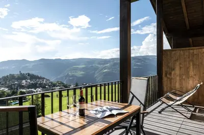 a table with a bottle of wine on a balcony at Appartements Panorama in Fiè