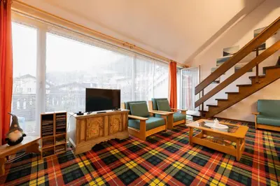 a living room with a couch and a tv and a staircase at Cesa Molin in Campitello di Fassa
