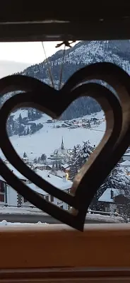 a heart shaped window with a view of a city at Garni Sayonara in Moena