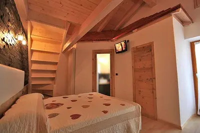 a bedroom with a bed and a tv on a wall at Garni Sayonara in Moena