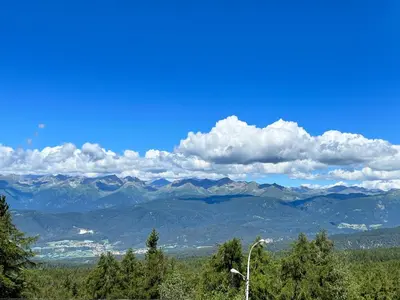 a view of a mountain range with a blue sky and clouds at PanoramaHotel Penegal in Mendola