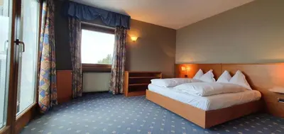 a hotel room with a bed and a window at PanoramaHotel Penegal in Mendola