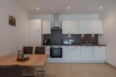 a kitchen with white cabinets and a wooden table at Residence Weinberg 8 in Nalles