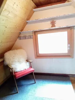 a room with a red chair and a window at Il nido (Cica) in Sottoguda